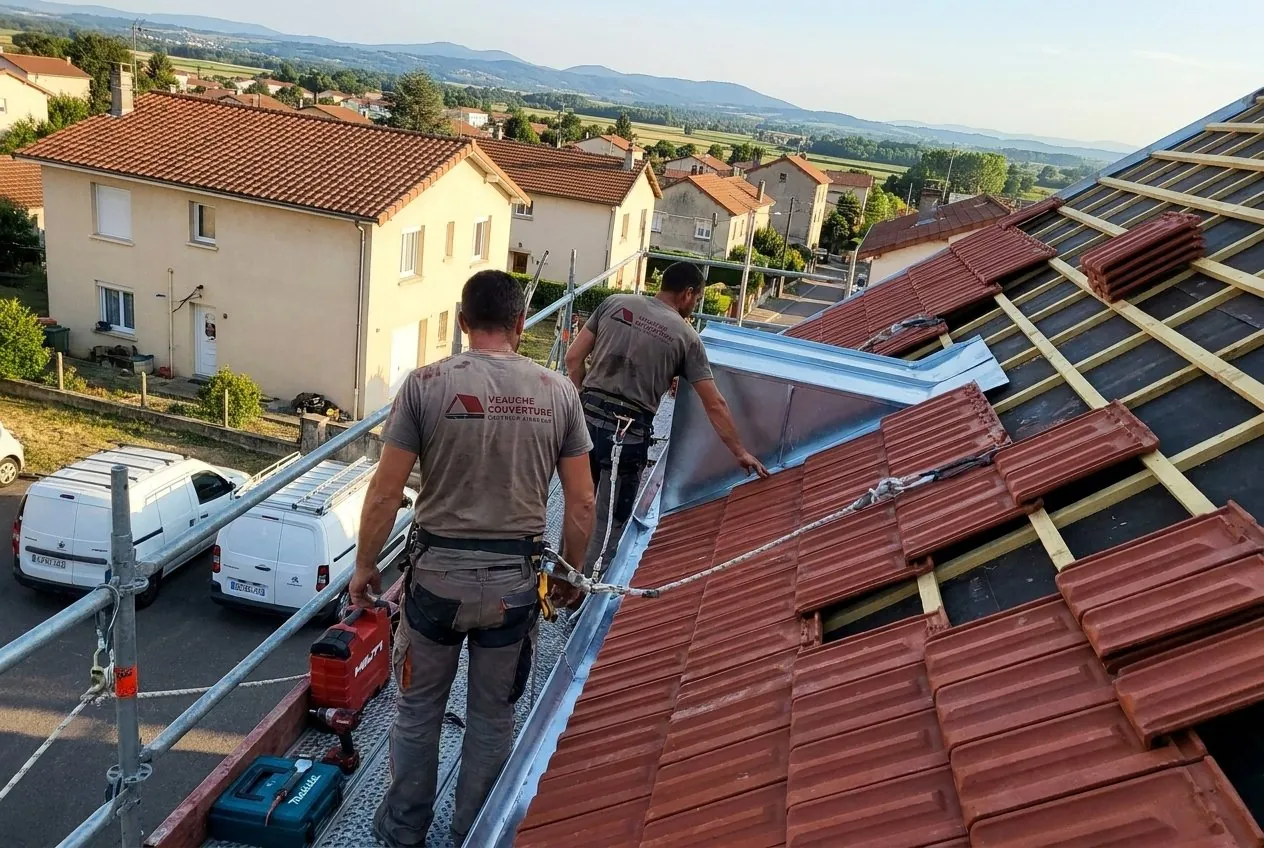 Couvreurs de Veauche Couverture posant des tuiles mécaniques rouges et une noue en zinc à Veauche, plaine du Forez en fond